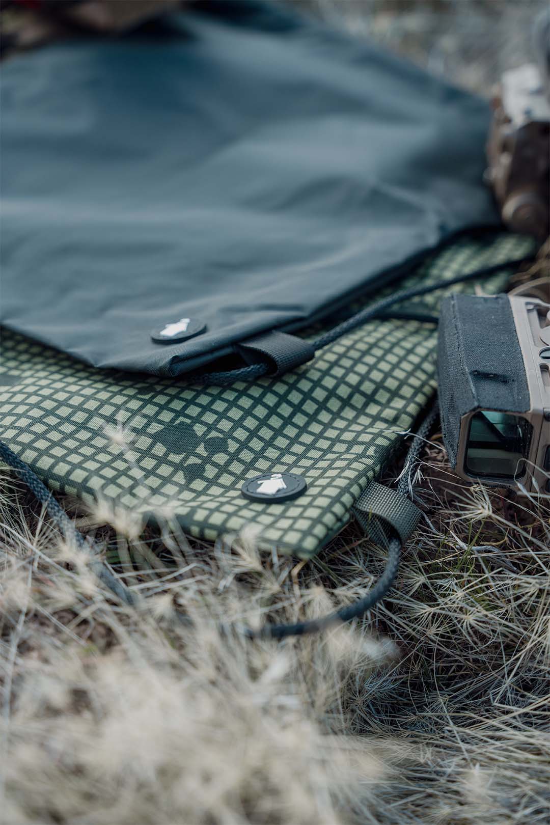 Green and black patterned bag with a device on grass