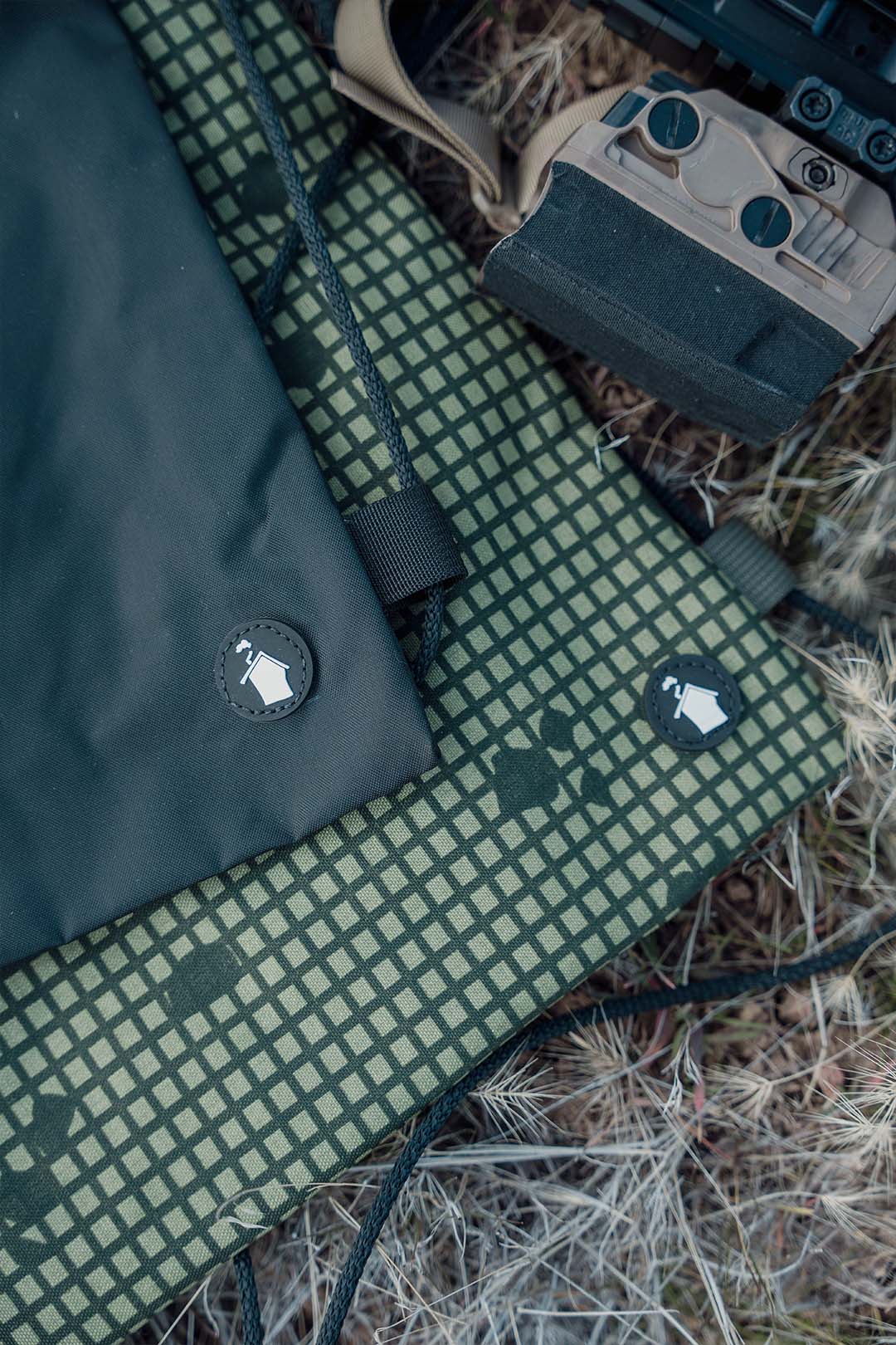 Green checkered mat with a black bag and a device on a grassy background