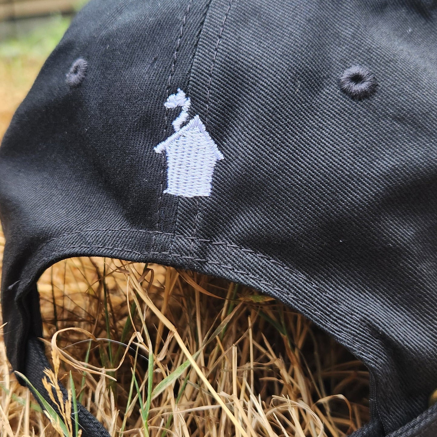 Black cap with a logo on a hay bale