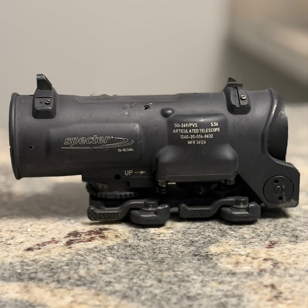 A black Specter 50mm 5Wx LED Artillary Telescope mounted on a black bipod, resting on a speckled granite countertop.